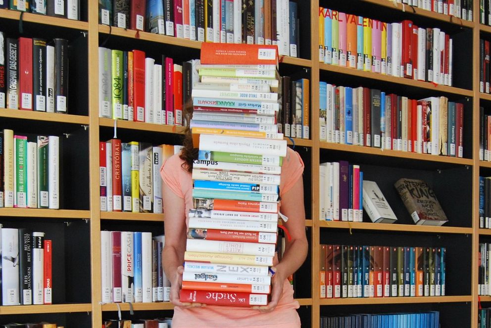 Studentin mit vielen Büchern auf dem Arm