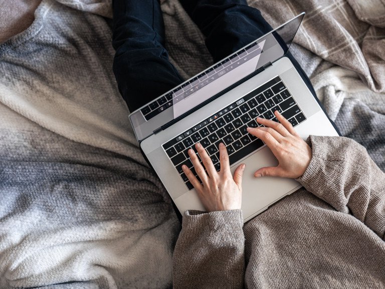 [Translate to Englisch:] working on a laptop while lying in bed