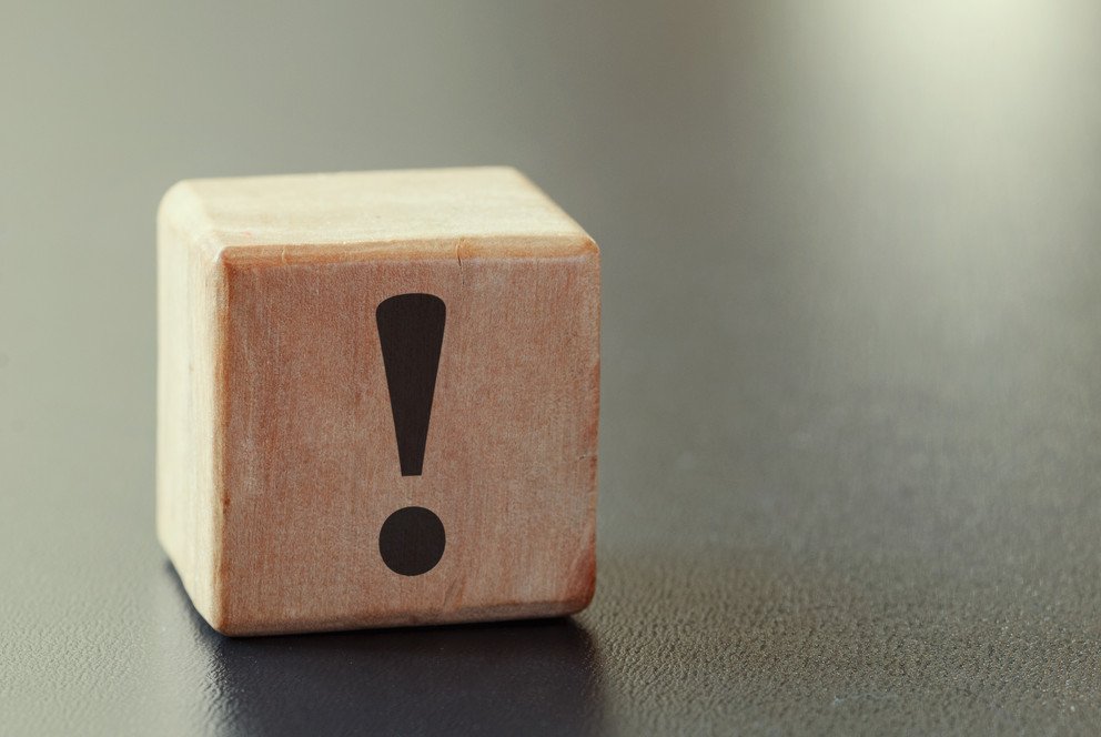 Symbolbild f&uuml;r eine wichtige Information, dargestellt durch einen Holzw&uuml;rfel auf dem ein schwarzes Ausrufezeichen zu sehen ist