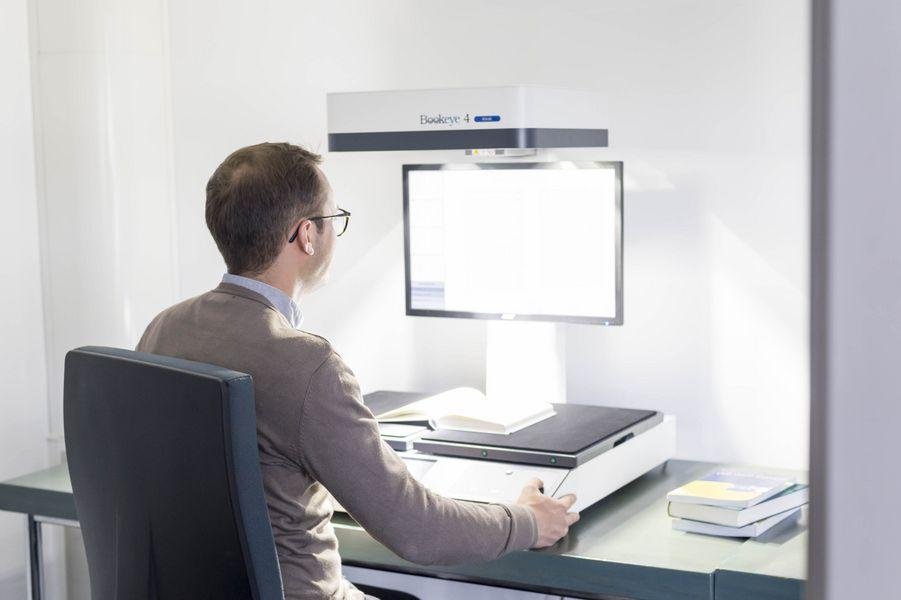 Eine Person sitzt vor einem Aufsichtsscanner Eine Person sitzt vor einem Aufsichtsscanner