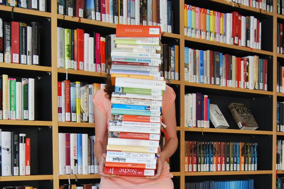Studentin mit vielen Büchern auf dem Arm