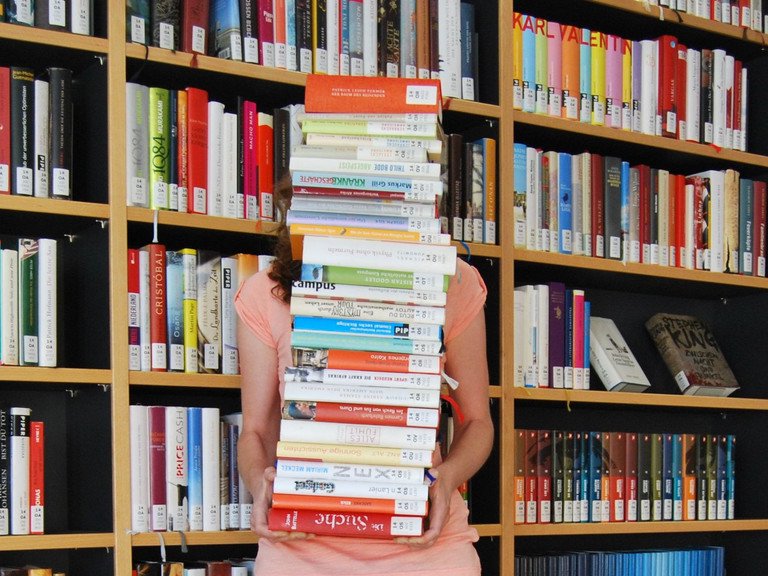 Studentin mit vielen B&uuml;chern auf dem Arm